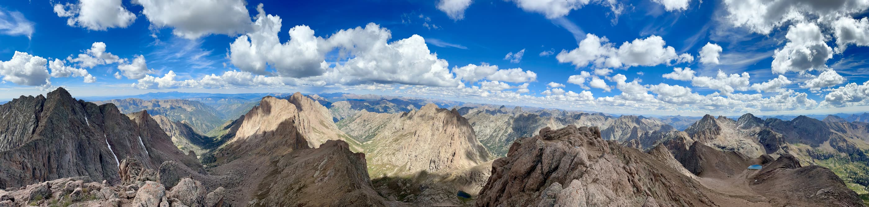 A long panorama of jagged mountain ridges under a sky full of clouds